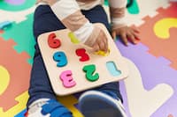 adorable-hispanic-toddler-playing-with-maths-puzzle-game-sitting-floor-kindergarten